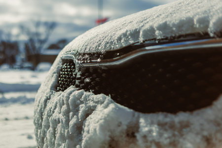 A car sits parked outside, covered in thick layers of snow. The winter weather creates a cold...