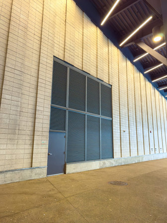 A large wall made of blocks shows a door on one side. Horizontal metal slats cover a section above...