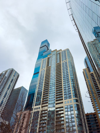 Tall buildings reach towards the sky in a bustling city area. The structures reflect light and...
