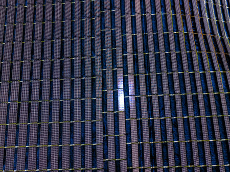 A vast layout of solar panels is visible under clear skies. The solar cells reflect sunlight,...