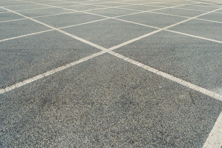 A large parking lot shows empty spaces and painted lines under bright daylight in a busy location.