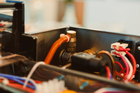 A technician works on machinery showing pipes and wires. The setting is a workshop where various...