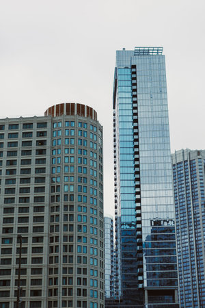 Tall buildings stand closely together under a cloudy sky in an urban area, showing modern...