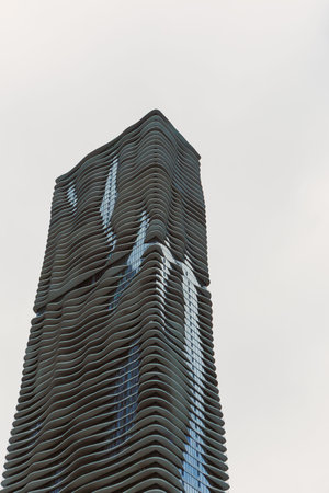 Tall building with a wavy pattern stands against the sky, capturing attention in a busy urban...