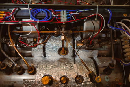 Metal components and wires connect inside an electric machine. The workshop is busy with tools used...