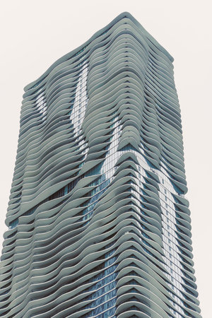 A modern building with a wavy shape stands tall against a cloudy sky in a city. Its unique design attracts attention.の写真素材