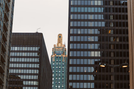 People walk on the street as tall buildings frame a sky view of a structure with a golden top during...