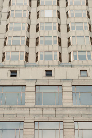 Tall building shows many windows and a textured surface in an urban area during bright daylight.