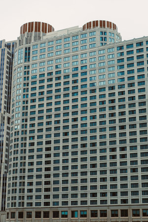 A tall building features numerous windows and a distinct design in a city area under daylight...
