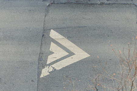 A white arrow is painted on the road surface indicating a right turn in a city setting. The asphalt...