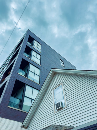 Two buildings are visible in the frame. One is modern with large windows and dark bricks. The other...
