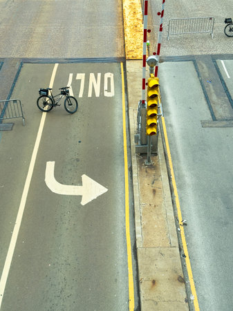 A parked bicycle stands beside a traffic signal on a city street while barriers are set up in the background.の写真素材