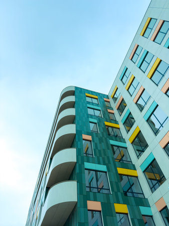 The picture shows a modern building with a mix of colors and shapes. It stands tall against the...