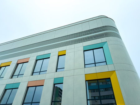 A modern building stands in an urban area. The structure has a smooth surface with different colored...