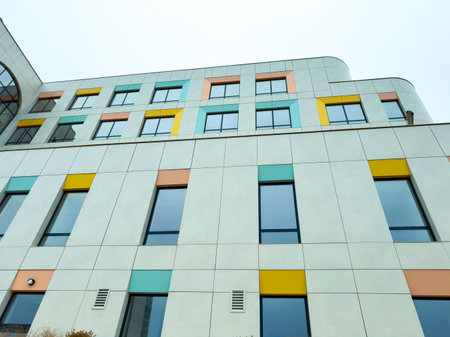 A structure stands tall with a mix of light colors and large windows. The design features colored...