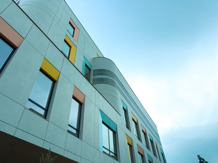 The view shows a modern building with a mix of colorful accents on the exterior. Large windows allow...