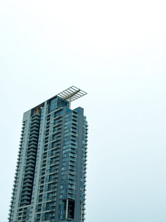 A high-rise residential building with many windows touches the clouded sky in a city.