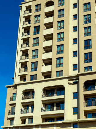 A tall building stands with multiple floors. The structure has many windows and balconies. The sky...