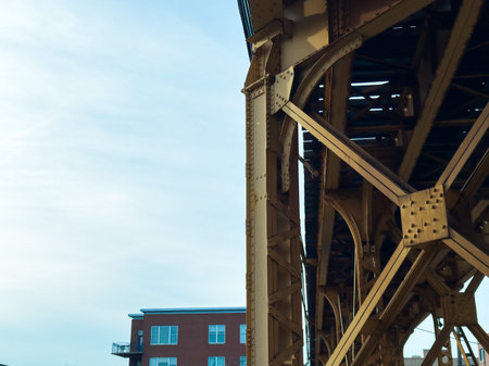A large steel structure holds train tracks overhead in a city. Below, red brick buildings offer a...