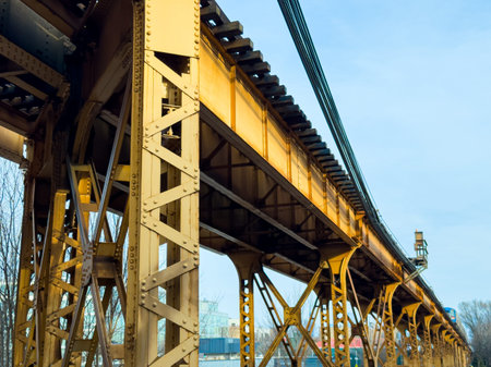 A yellow railway bridge connects two land areas with train tracks running along the top. An...