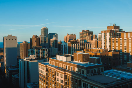 A person stands on a rooftop taking in the view of the city skyline at sunset. The sun casts shadows...