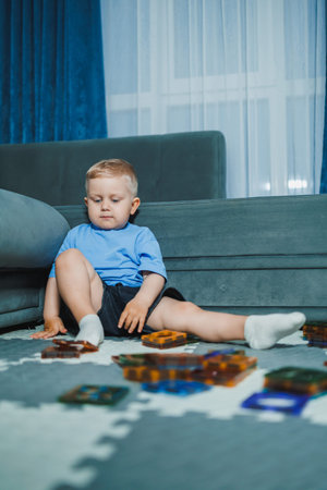 A young child sits on the floor near a couch, focused on arranging colorful building blocks. The...