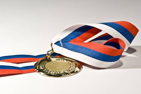 Studio close-up photo of golden medal with tricolour ribbon isolated on white backgroundの写真素材