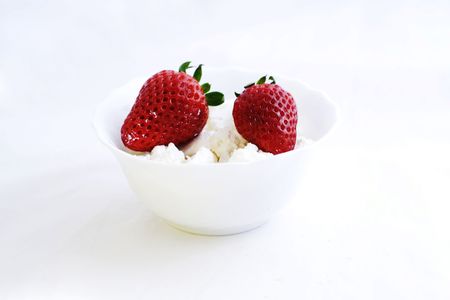 Studio shot of cottage cheese and two strawberries. Milk products isolated on white background.の写真素材