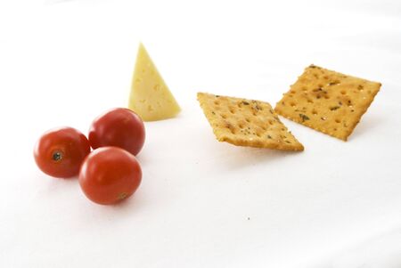 Studio shot of solt crackers with green, cherry tomatoes and cheese isolated on white background