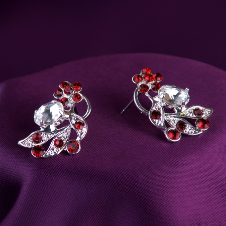 silver earrings with red gemstones on purple silk backgroundの写真素材