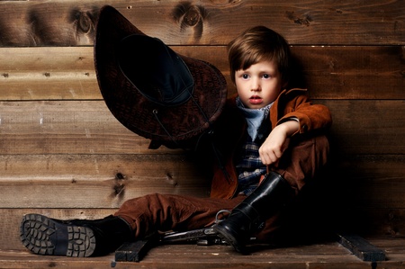 studio portrait of little cowboy holding his hat in handの写真素材