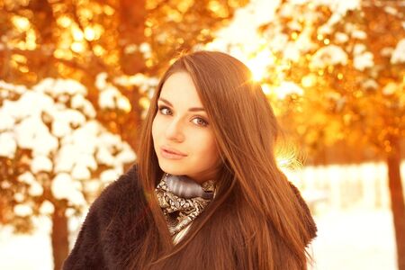 winter portrait of young beautiful girl against golden bokeh background