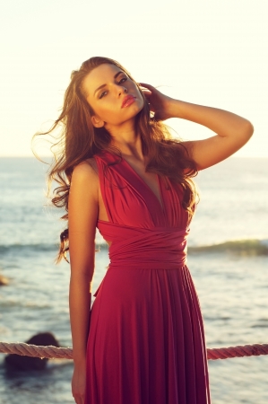 young beautiful elegant woman in pink dress standing near seaの写真素材