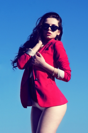 fashion portrait  sexy girl in red coat posing against blue skyの写真素材