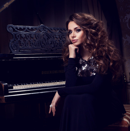 Beautiful thoughtful girl sitting near pianoの写真素材