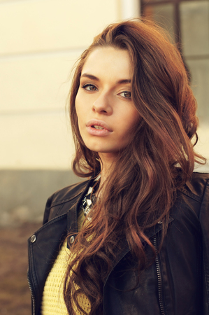 young beautiful woman wearing dress, yellow pullover and leather jacket posing outdoors. stylish fashion portrait       の写真素材