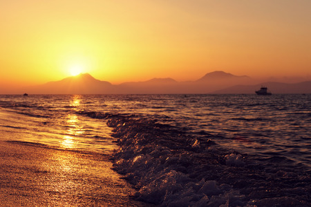 sandy beach and sea ay sunset with mountains at horizonの写真素材