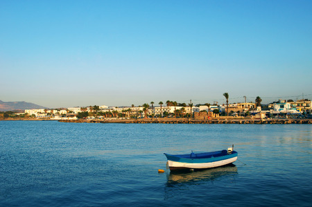 Small boat in calm harbor at sunset.の写真素材