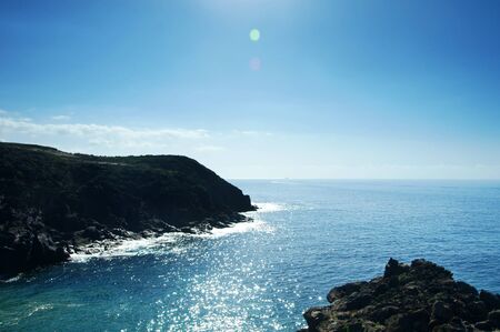 view on calm atlantic blue or azure ocean water and rocks of coastline on a sunny day at south coast...