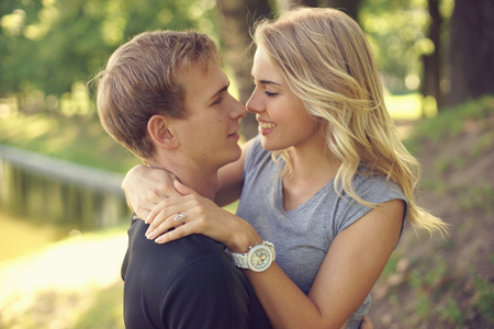 Romantic caucaian  couple hugging in park. Young beautiful blonde girl looking at her boyfriendの写真素材