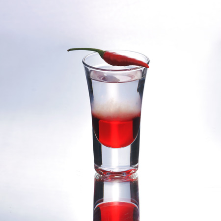 Colorful layered shot with reflection. Alcohol red shooter with chili pepperの写真素材