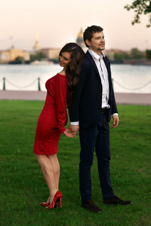 Young stylish couple standing at green grass near river in city.の写真素材