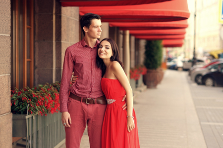Young romantic couple standing and hugging at city street on a sunny summer eveningの写真素材