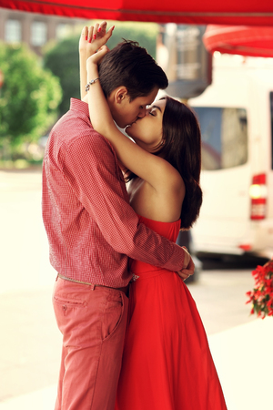 Young stylish romantic couple standing and kissing at city street on a summer sunny eveningの写真素材