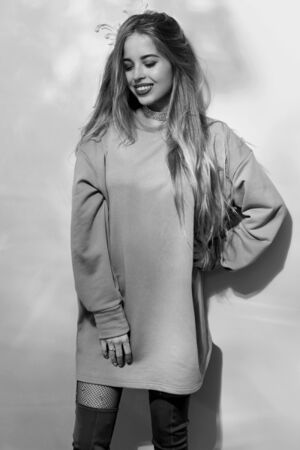 Young pretty cute woman with long straighthair in gray sweatshirt, grid pantyhose and hessian boots.の写真素材