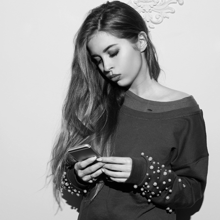 Pretty stylish girl in sweatshirt, hessian boots, grid pantyhose and skirt standing near pink wallの写真素材