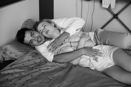Young romantic couple relaxing and hugging in bed. Pretty beautiful blonde girl and brunette man....