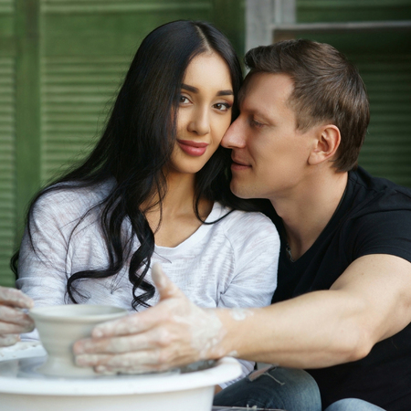 Romantic caucasian couple sculpring clay at pottr wheel. Making pottery together.の写真素材