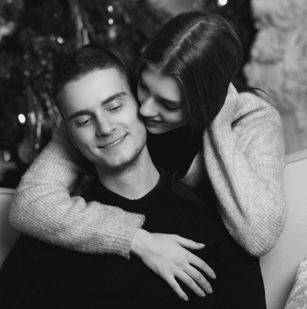 Young romantic cute couple staing at home and enjoying time together. Lovers hugging in cristmas decorated interiorの写真素材