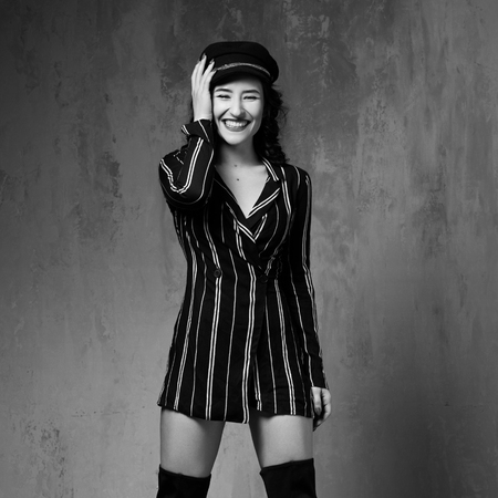 Full length fashion style portrait of young attractive black haired woman wearing striped dress and...